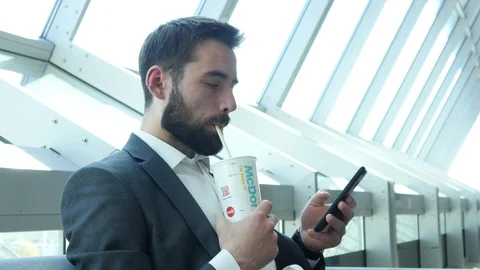 Business Man with Beard on a Face use Mobile Phone and drinks McDonald's Cola  Stock Footage 106788293