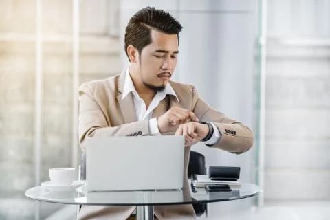 Business man checking time on smart watch while using laptop 写真素材