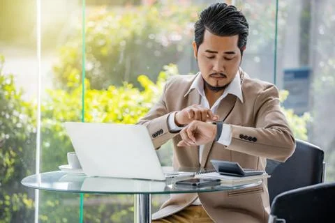 Business man checking time on smart watch while using laptop Stock Photos