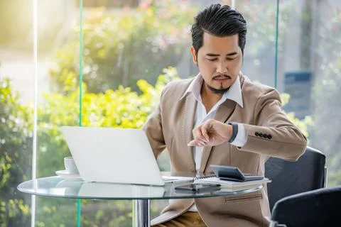 Business man checking time on smart watch while using laptop Stock Photos