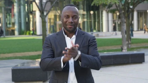 Business man claps while smiling and staring into camera outdoors - slow motion Stock Footage 124080911
