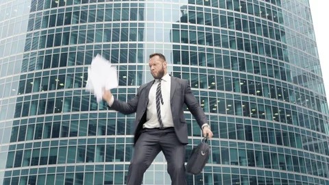 Business man dancing and throwing papers near the office building Stock Footage 111220207