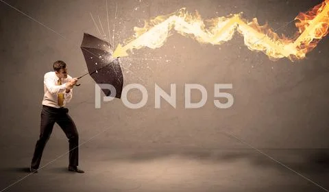 Business man defending himself from a fire arrow with an umbrella Stock Photos