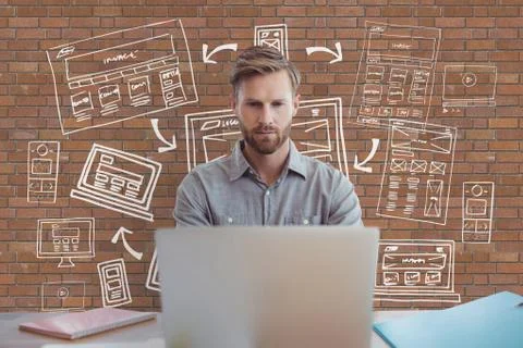 Business man at a desk using a computer against brick wall with graphics Stock Photos