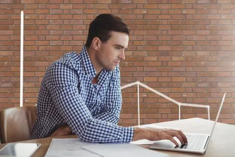 Business man at a desk using a computer against brick wall with graphics 스톡 사진