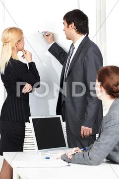 A business man drawing a plan on a whiteboard for his colleague Stock Photos