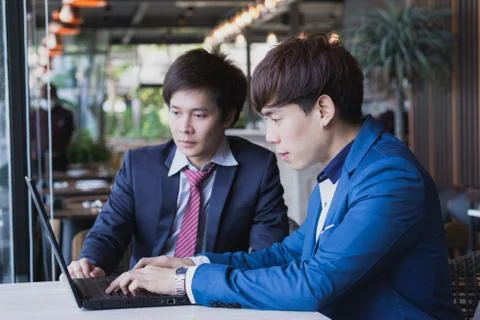 Business man explaining about project with caucasian colleague while typing k Stock Photos