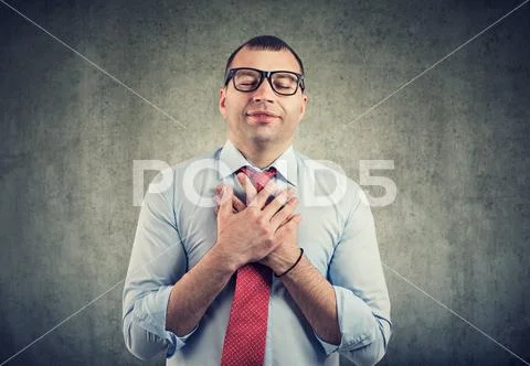 Business man with eyes closed keeps hands on chest near heart, shows kindness Stock Photos