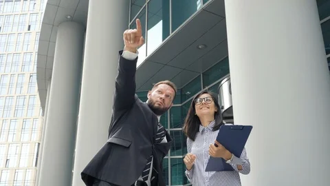 Business man gesticulating and explaining something to the young woman outdoors Stock Footage 110745427