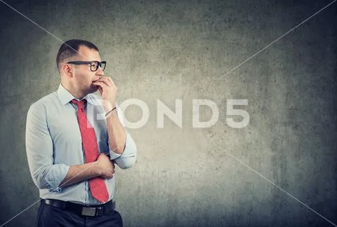 Business man in glasses biting nails being in panic and anxiety looking to th Stock Photos