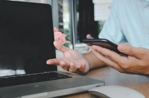 Business man hand using mobile smart phone and computer laptop on table.sea.. Stock Photos
