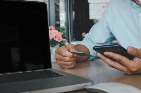 Business man hand using mobile smart phone and credit card with computer la.. Stock Photos