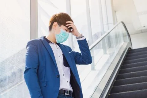The business man has a headache while standing on the escalator from coronavi Stock Photos