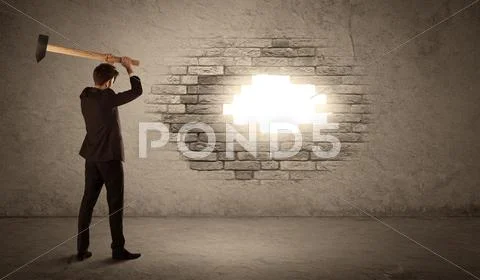 Business man hitting brick wall with hammer and opening a hole Stock Photos