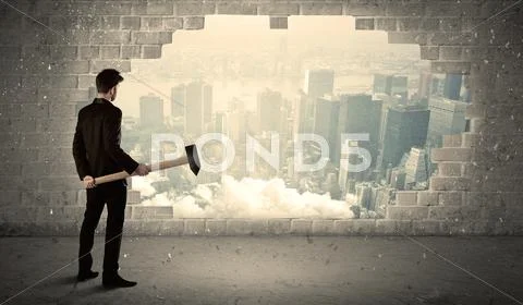 Business man hitting wall with hammer on city view Stock Photos