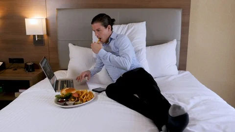 Business man on hotel bed eats food and works on laptop Video stock 94259291