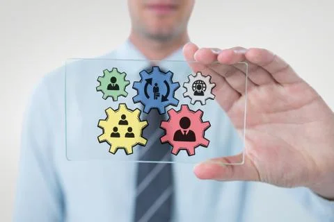 Business man interacting with people in cogs graphics against white background Stock Photos