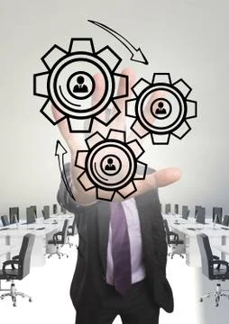 Business man interacting with people in cogs graphics against office background Stock Photos