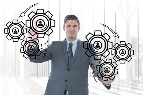 Business man interacting with people in cogs graphics against office background Stock Photos