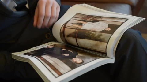 Business man leafing through a glossy magazine while sitting on the couch Stock Footage 48370690