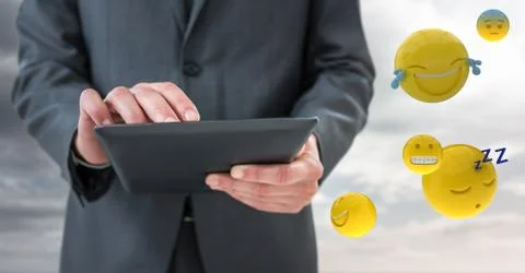 Business man mid section with tablet next to emojis and flare against cloudy sky Stock Photos
