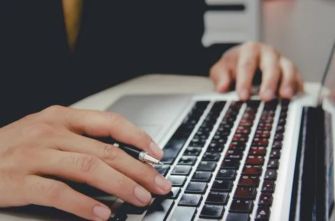 Business man with a pen on a notebook computer keyboard Stock Photos