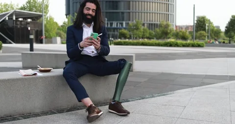 Business man with prosthetic leg using mobile phone outdoor Stock Footage 195106538