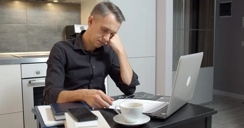 Business man reading documents and working on laptop at home Stock Footage 127020663