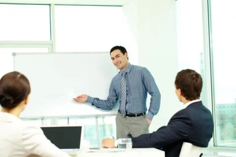 A business man showing something on a whiteboard to his colleagues Stock Photos