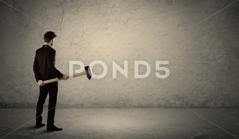 Business man standing in front of a grungy wall with a hammer Stock Photos