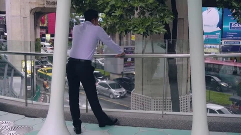 Business man standing at railing overlooking traffic in city Stock Footage 81620296