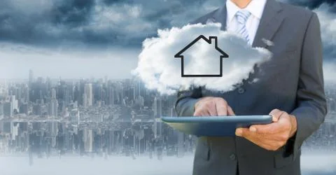 Business man with tablet and cloud with house against blurry skyline Foto stock