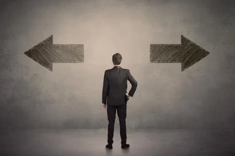 Business man taking a decision while standing in front of two grungy arrows o Fotos Stock