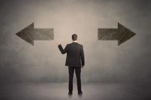 Business man taking a decision while standing in front of two grungy arrows o Fotos Stock