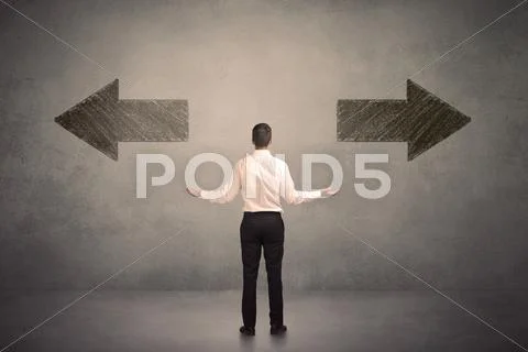 Business man taking a decision while standing in front of two grungy arrows o Stock Photos