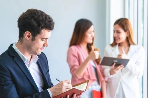 Business man is taking note in front of two female office worker 库存照片