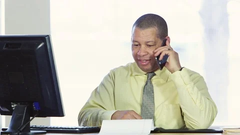 Business man talking on cellphone and looking at computer Stock Footage 80227398