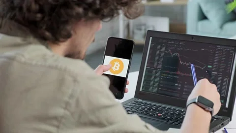 Business man trader using mobile phone app and laptop analytics. Stock Footage 169399665