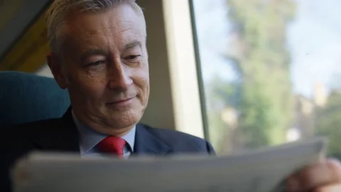 Business man on a train checking share prices in a paper, in slow motion Free Stock Footage 83648774