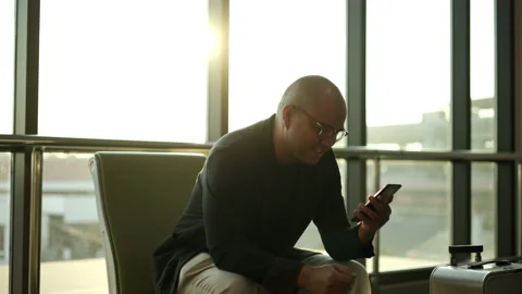 Business man using cell phone while waiting for a flight in airport. Smart Asian Stock Footage 168729021