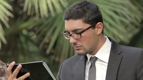 Business man using a digital tablet device while standing in a tropical zone Stock Footage 32579085
