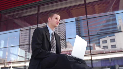 Business Man using Laptop in Front Of Glass Building Vidéo 22760877