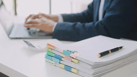 Business man using laptop while working on pile of documents Stock Footage 325474667
