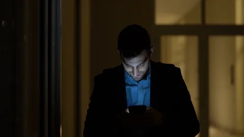 Business man using mobile alone in dark office Stock Footage 88560276
