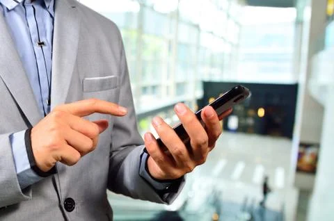 Business Man using Mobile Cell Phone in The Modern office building. Stock Photos