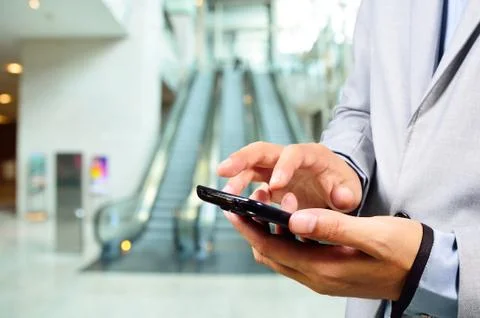 Business Man Using Mobile while going down Escalator Stock Photos