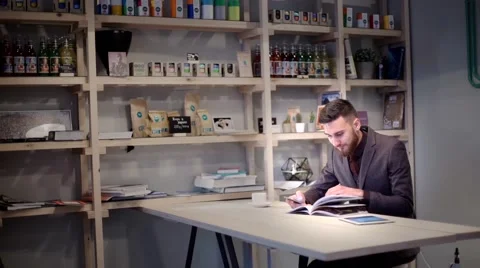 Business man is using smart phone and read magazine in cafe with e-cigarette Stock Footage 56892133
