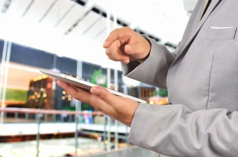 Business man using tablet device on blurred abstract bokeh background as comm Stock Photos