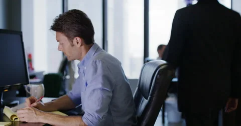 Business man writes on yellow notepad as boss visits co-workers behind 4K Stock Footage 67261334