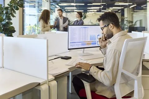 Business manager analyzing spreadsheet data at desktop monitor in bright office Stock Photos